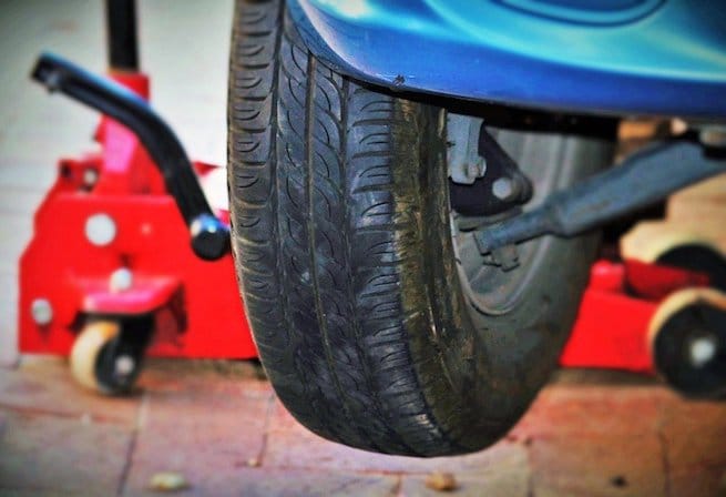 Tire change with car floor jack on the background