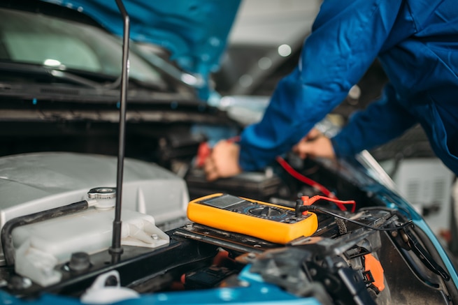 Auto electrician checks the battery level