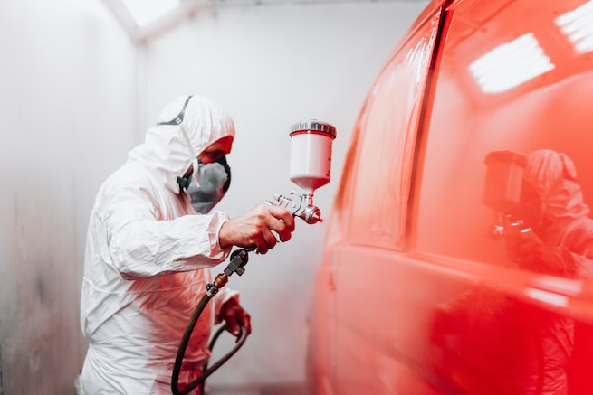 Auto manufacturing industry worker with spray gun with red paint