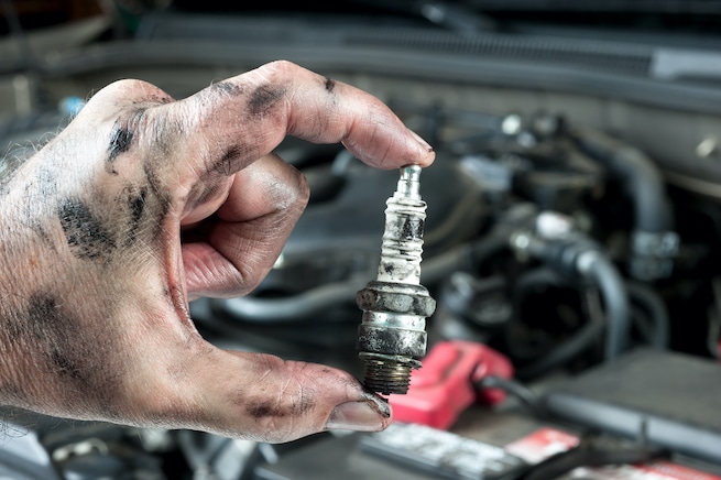 Mechanic replacing bad spark plugs in a car